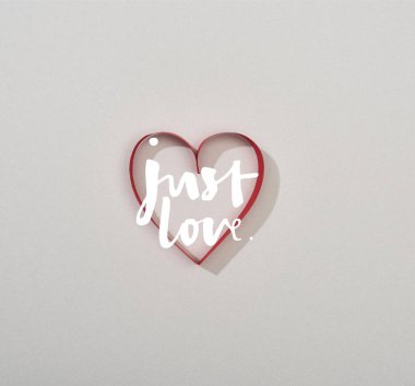 Top view of red paper heart on grey background with just love lettering clipart