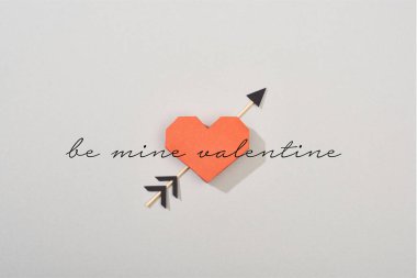 Top view of decorative paper heart with arrow and be mine valentine lettering on grey background