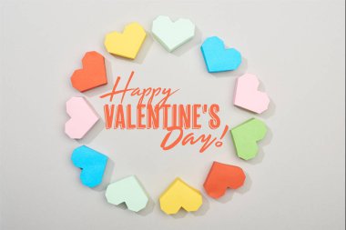Top view of frame of colorful paper hearts on grey background with happy valentines day lettering