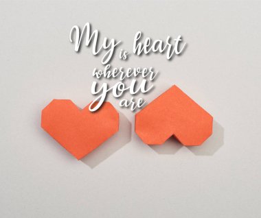 Top view of two red paper hearts on grey background with my heart is wherever you are illustration