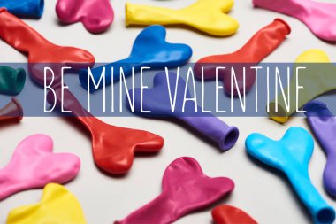 Colorful heart shaped balloons on grey background with be mine valentine lettering