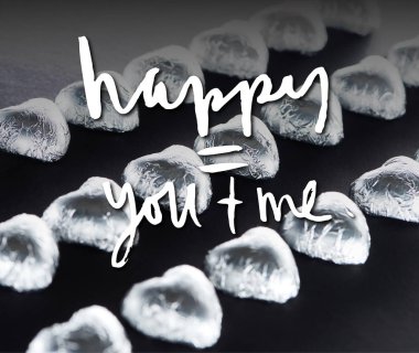 Heart shaped candies in foil on black background with happy you and me lettering clipart