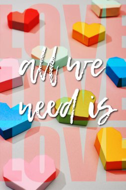Decorative multicolored hearts on grey background with all we need is love illustration