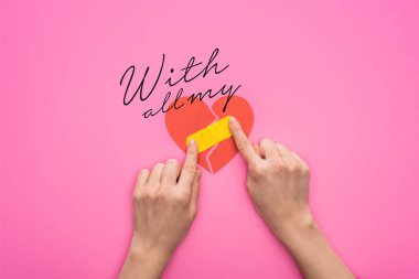 Kırık kalbe yama yapan, pembe arka planda izole edilmiş kadın görüntüsü.