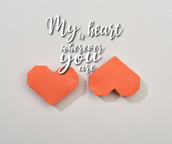 Top view of two red paper hearts on grey background with my heart is wherever you are illustration