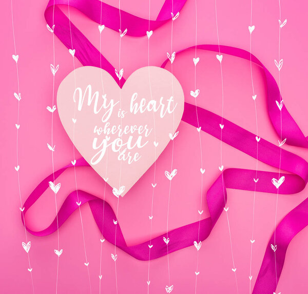 top view of paper heart with my heart is wherever you are illustration and ribbon isolated on pink