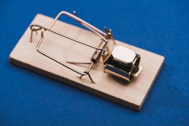 Mavi yüzeydeki fare kapanındaki parlak mücevher yüzüğünün görüntüsünü kapat