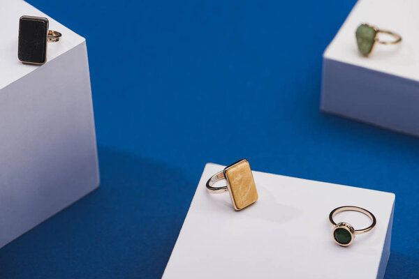Close up view of jewellery rings on white cubes on blue background