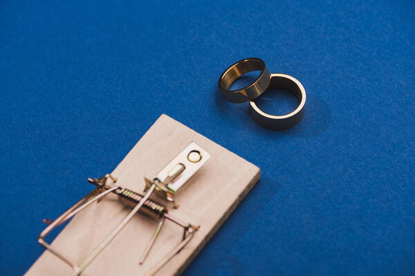 Selective focus of two golden rings with mouse trap on blue background