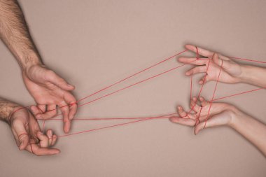 Bej arka planda kırmızı iplik tutan kadın ve erkeğin üst görüntüsü