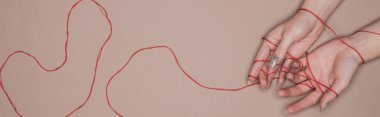 Top view of female hands with red string on beige background, panoramic shot clipart