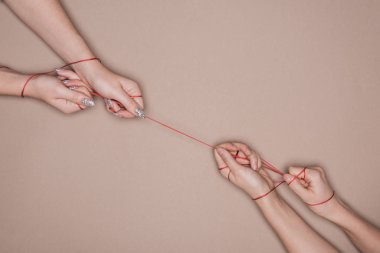 Top view of women pulling red string on beige background clipart