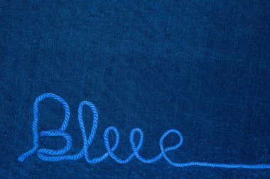 Mavi kumaş üzerindeki iplikten mavi sözcüğün üst görünümü