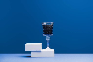 Klasik mavi arka planda, küplerde şarap kadehinde koyu mavi içecek.