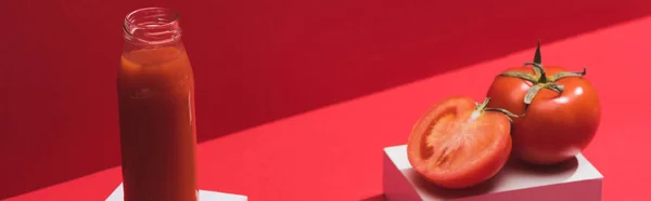 ガラス瓶の中の新鮮な野菜ジュースと赤い背景のキューブに熟したトマト パノラマショット — ストック写真
