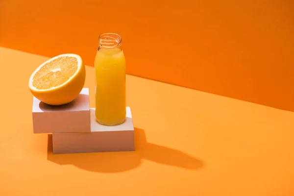 橙子半边的玻璃瓶里有新鲜果汁 橙子底上有白色立方体 — 图库照片