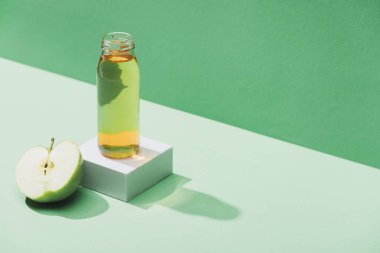 fresh juice near apple half and and white cube on green and turquoise background