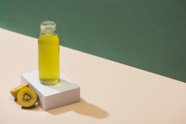 fresh juice near kiwi and and white cube on green and white background