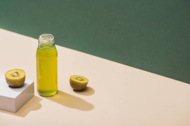 fresh juice near kiwi and and white cube on green and white background