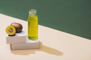 fresh juice near kiwi and and white cubes on green and white background