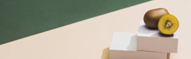 kiwi and and white cubes on green and white background, panoramic shot