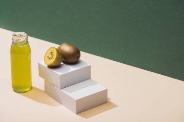 fresh juice near kiwi and and white cubes on green and white background
