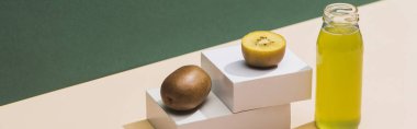 fresh juice near kiwi and and white cubes on green and white background, panoramic shot