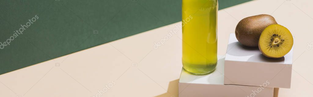 Fresh juice near kiwi and and white cubes on green and white background, panoramic shot
