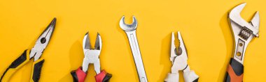 Top view of wrenches and pliers on yellow background, panoramic shot clipart
