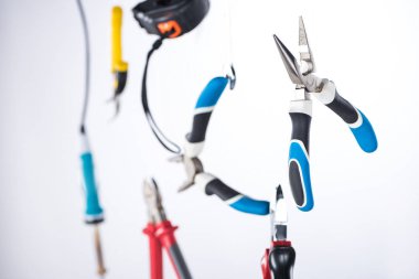 Selective focus of pliers and tools levitating in air isolated on grey clipart