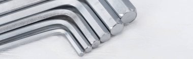 Close up view of hex keys on white wooden background, panoramic shot clipart