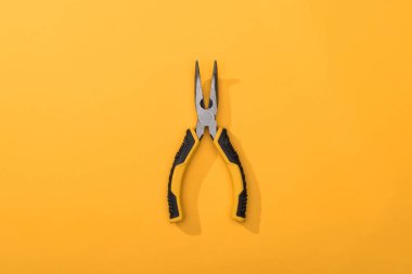 Top view of pliers on yellow background clipart