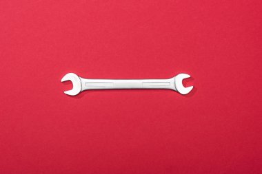 Top view of metal wrench on red background clipart