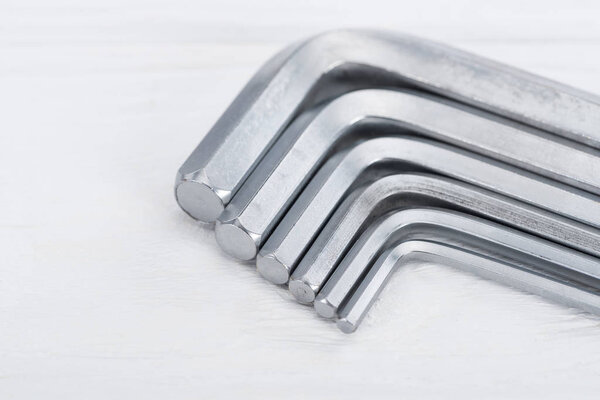 Close up view of hex keys on white wooden surface with copy space