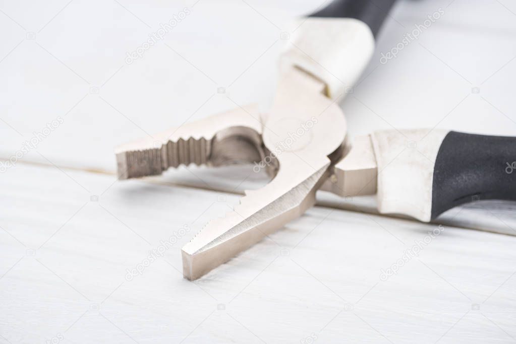 Close up view of pliers on white wooden background