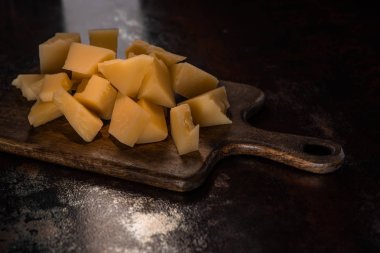 Güneş ışığında aşınmış yüzeyde Grana Padano peyniri olan ahşap tabaklar.