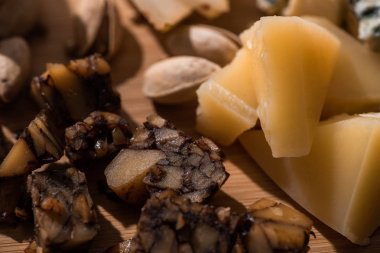 Fındık peyniri ve grana padano parçalarının seçmeli odak noktası kesme tahtasındaki şam fıstıklarının yanında.