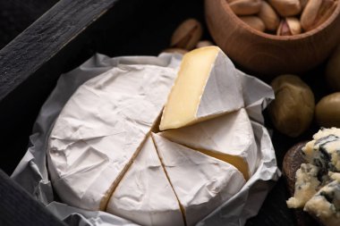 Dorblu, kurutulmuş zeytinli ve tepside şam fıstıklı Camembert dilimleri.