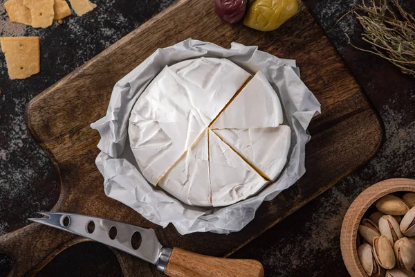 オリーブ クラッカー ピスタチオをナイフの近くに盛り付けたブリーチーズの上からの眺め — ストック写真