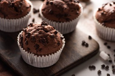 close up view of fresh chocolate muffins with marshmallow on wooden cutting board