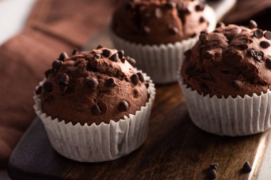 close up view of fresh chocolate muffins on wooden cutting board