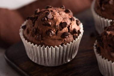 close up view of fresh chocolate muffin on wooden cutting board