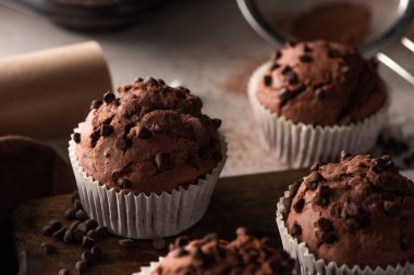 close up view of fresh chocolate muffins on wooden cutting board