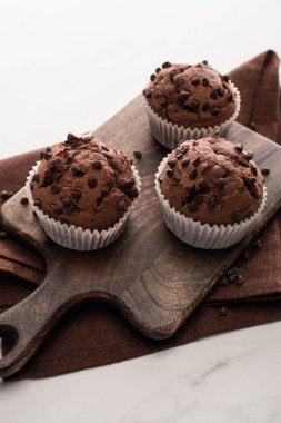 fresh chocolate muffins on wooden cutting board on brown napkin