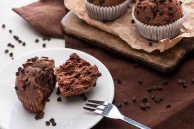 fresh chocolate muffins on wooden cutting board and plate with fork