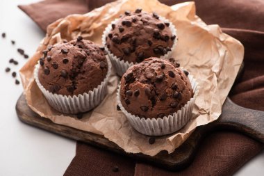 fresh chocolate muffins on wooden cutting board on brown napkin