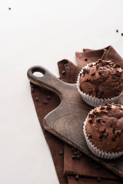 fresh chocolate muffins on wooden cutting board on brown napkin