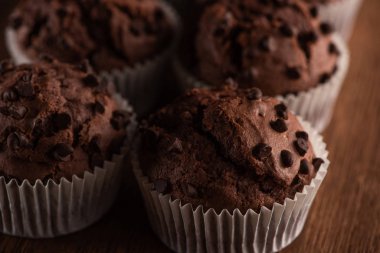 close up view of fresh chocolate muffins on wooden surface