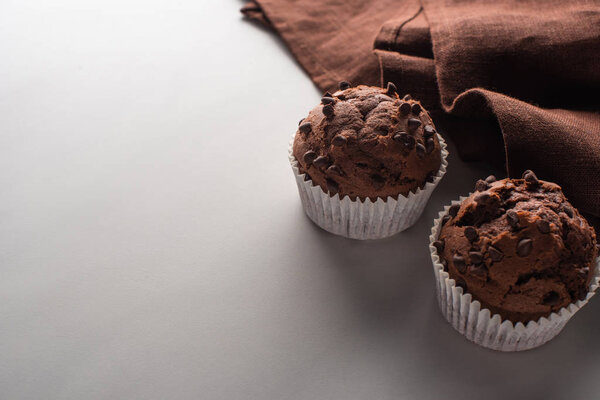 fresh chocolate muffins with brown napkin on marble surface