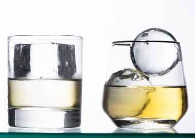 Altın sıvılı şeffaf bardaklar ve beyaz üzerine izole edilmiş buz.